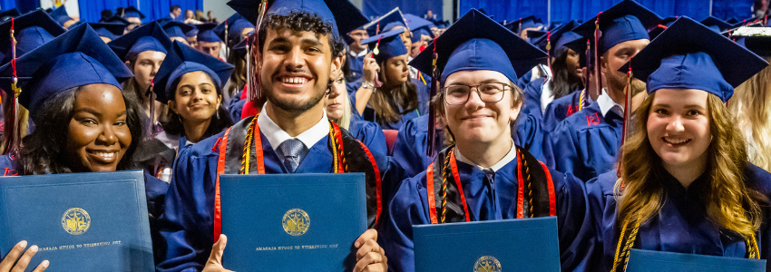 Four grads holding their diplomas.